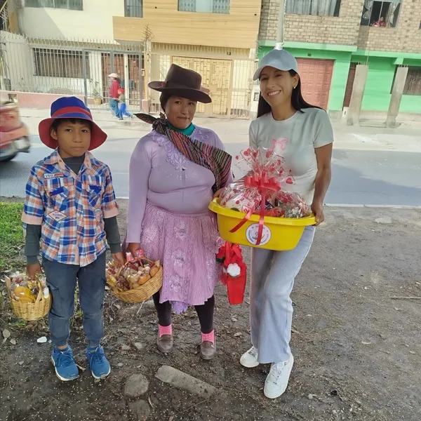 Madre y su hijo reciben una canasta de víveres de una voluntaria en la calle