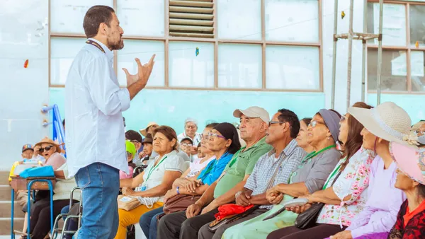 Voluntario dando una charla a un grupo de adultos mayores sentados