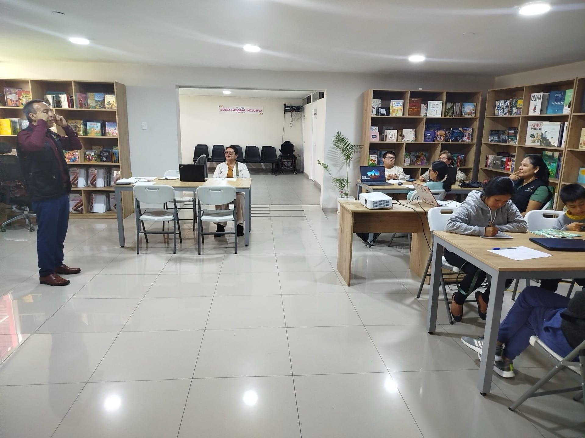 Participantes trabajando en mesas durante un taller en una biblioteca