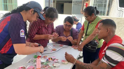 Voluntarias enseñando manualidades a señoras alrededor de una mesa