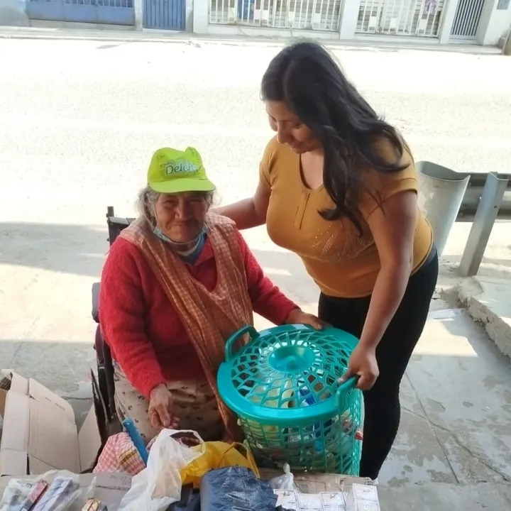 Voluntaria entregando una canasta a una señora mayor en la campaña del Día de la Madre
